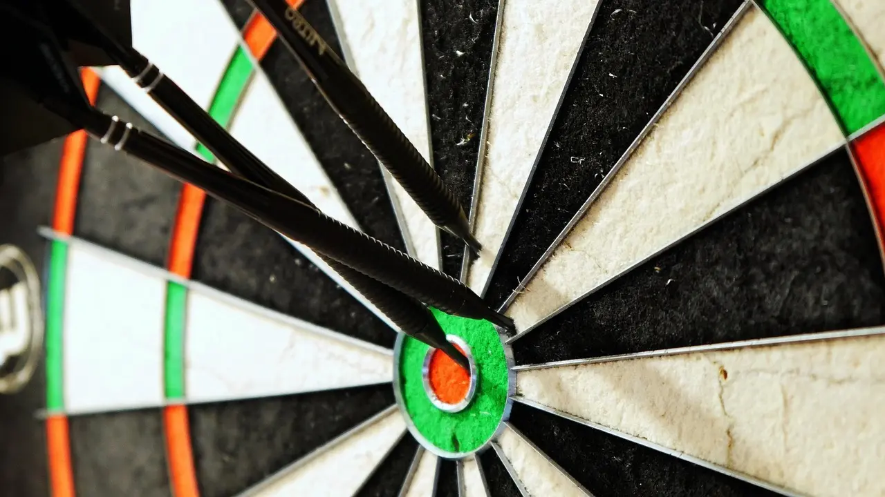 Tre dartpile i bullseye på et dartbræt